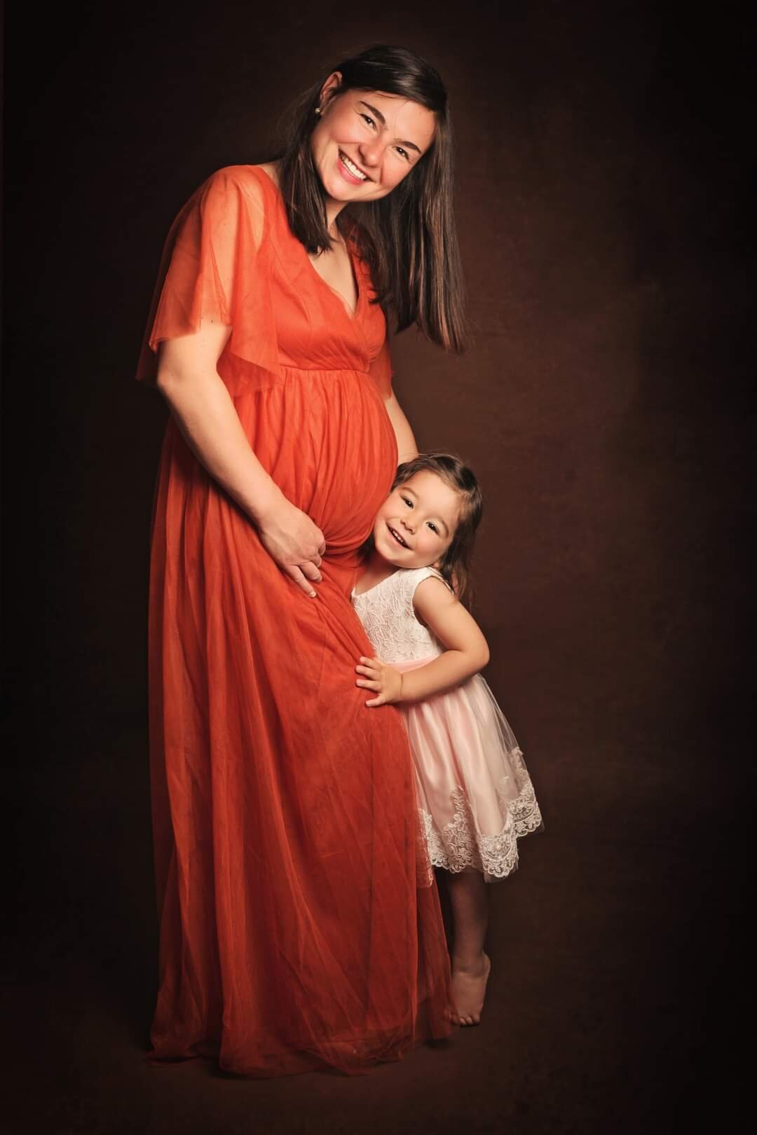 Future maman en robe orange avec sa fille
